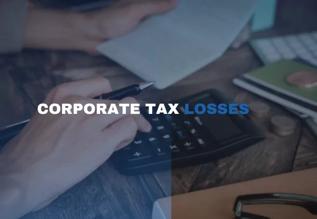 A person using a calculator and a pen in the background with text overlay "CORPORATE TAX LOSSES"