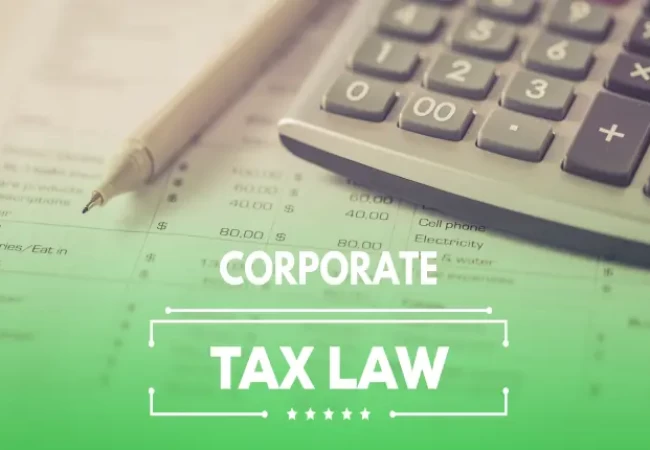 A calculator and pen rest on financial documents with the words "corporate tax law" superimposed on the image