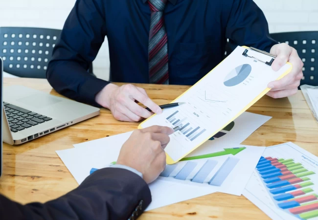 A person pointing at a graph on a clipboard