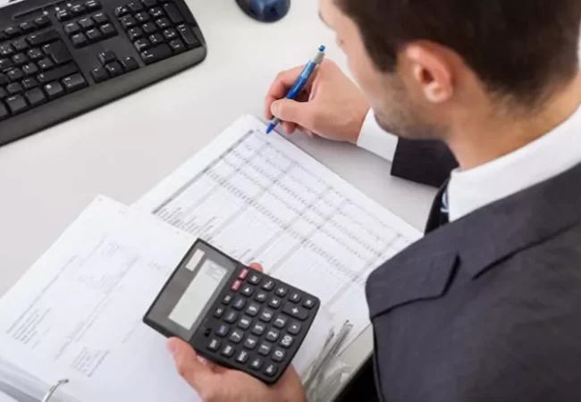 A person holding a calculator and pen