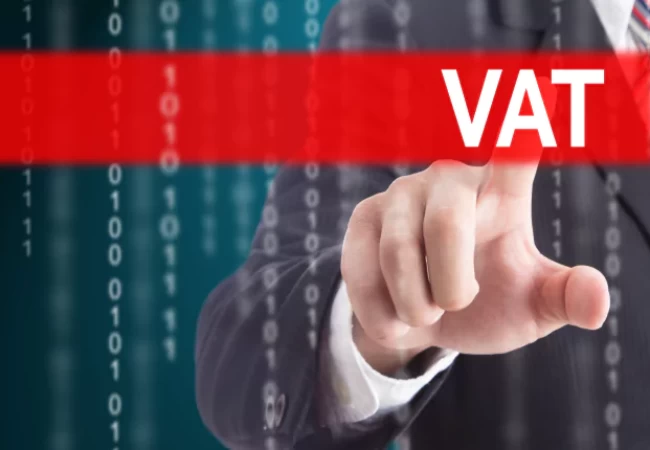 A person in a business suit gestures towards a virtual touch screen with the acronym "vat" highlighted in white text against a red background