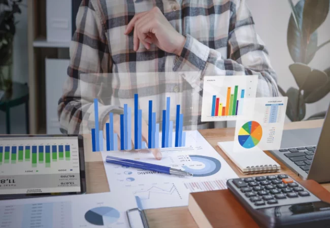 Person analyzing financial data and charts with a calculator on the desk